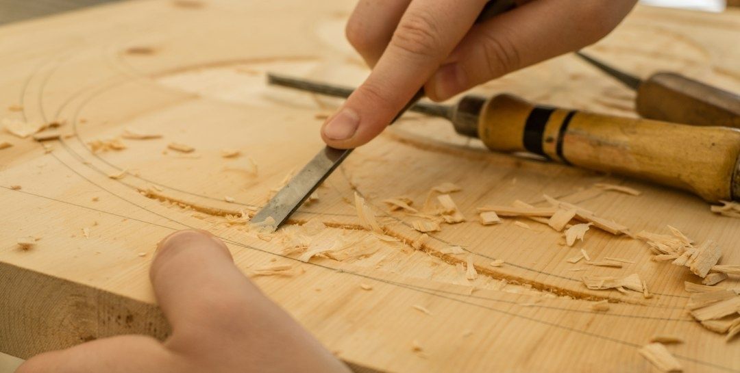 Hand carving a marked woodblock with a chisel amid wood shavings