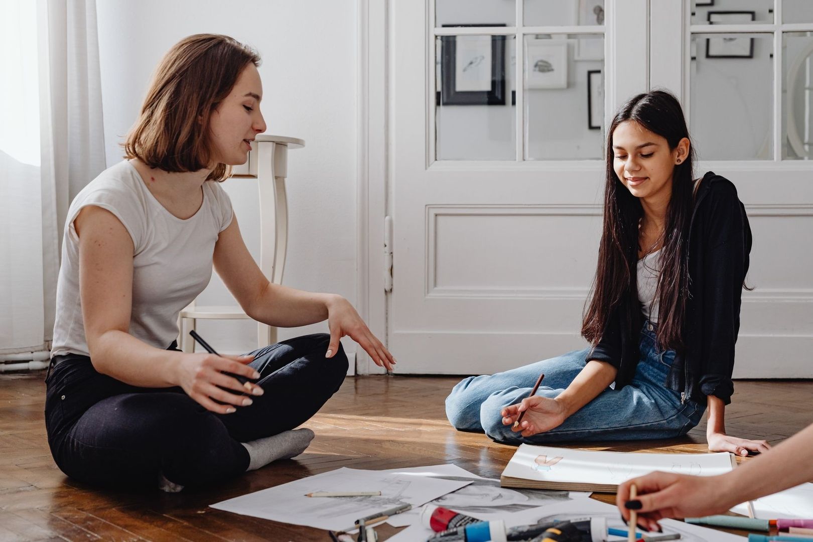 Artists sit together on the floor discussing drawings during a workshop